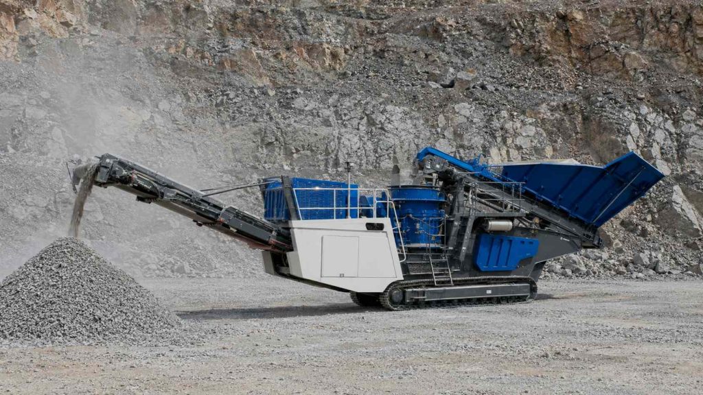 Mobile tracked cone crusher operating in a quarry with discharge conveyor producing crushed aggregate