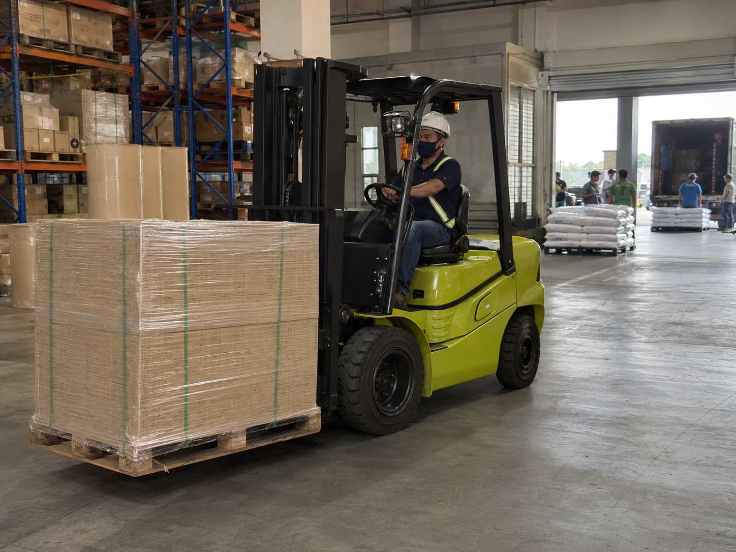 Forklift moving shrink-wrapped palletized materials inside a warehouse facility