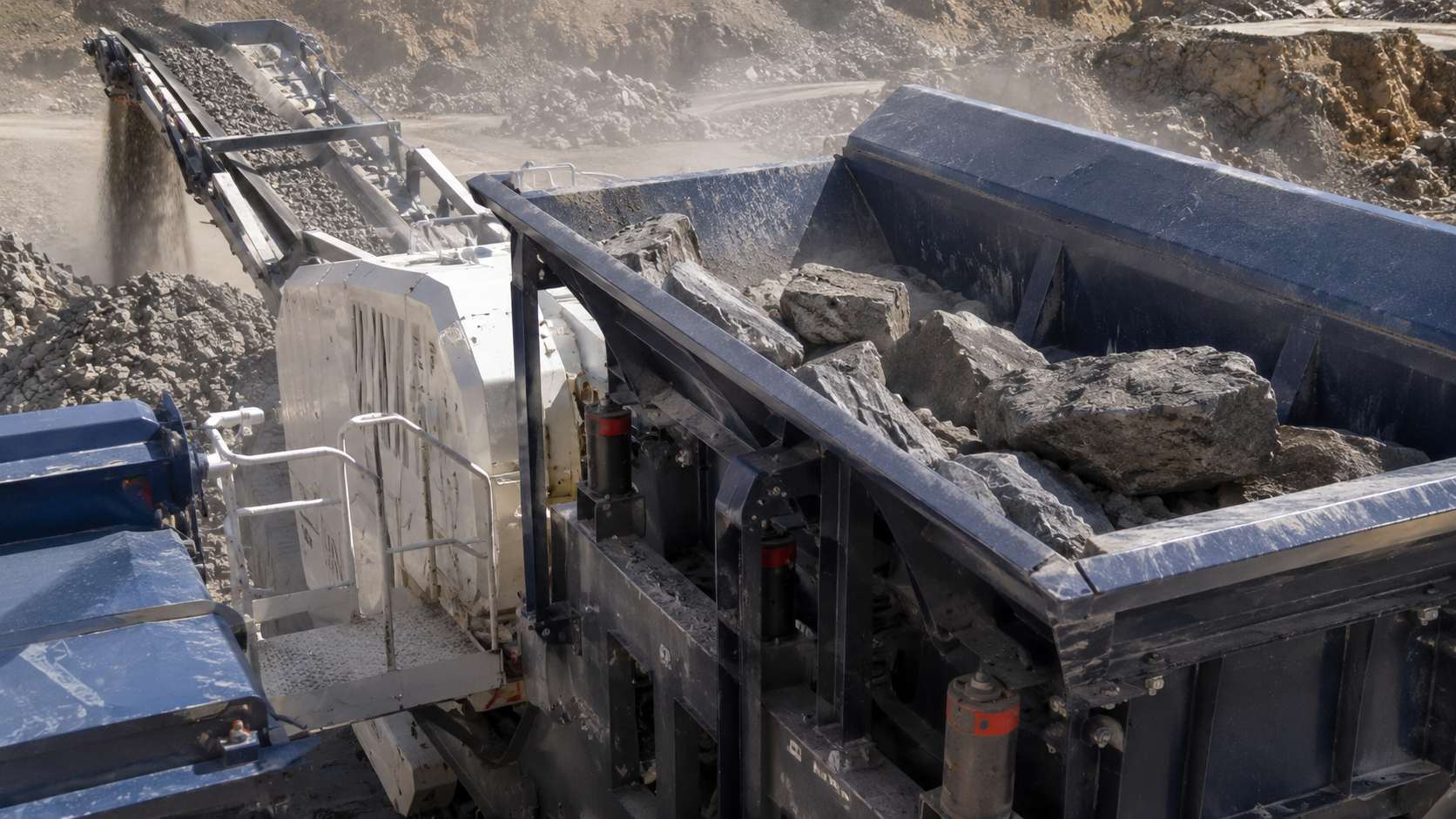Large rocks being fed into the intake hopper of a mobile jaw crusher for primary crushing
