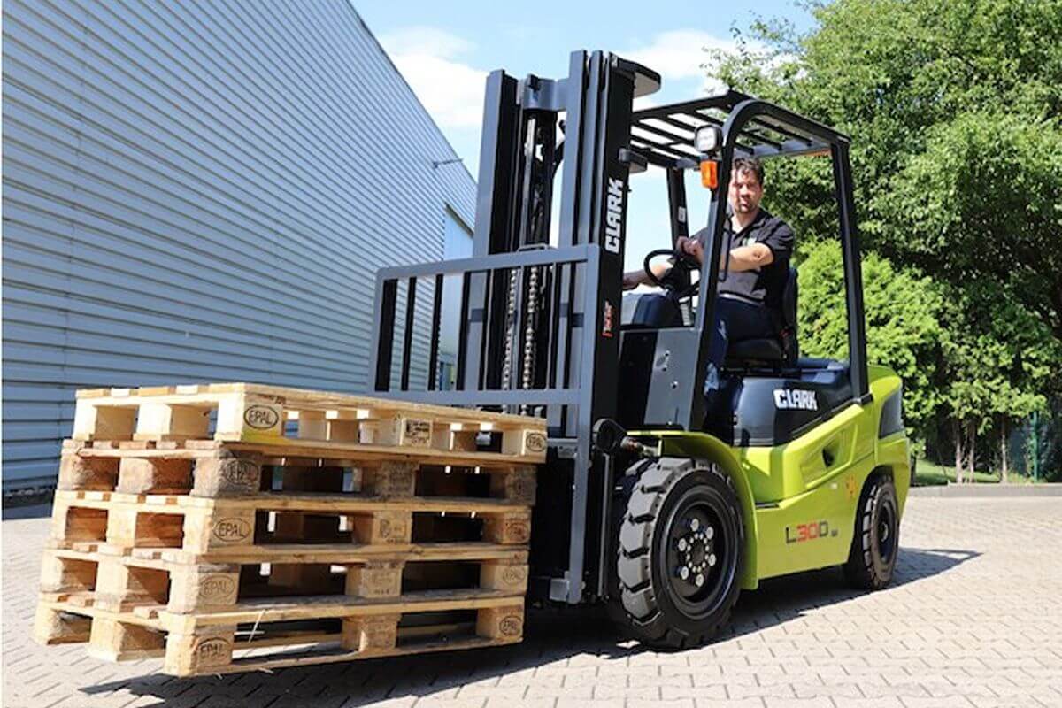 Clark forklift carrying wooden pallets outside a facility as an electric alternative for efficient material handling