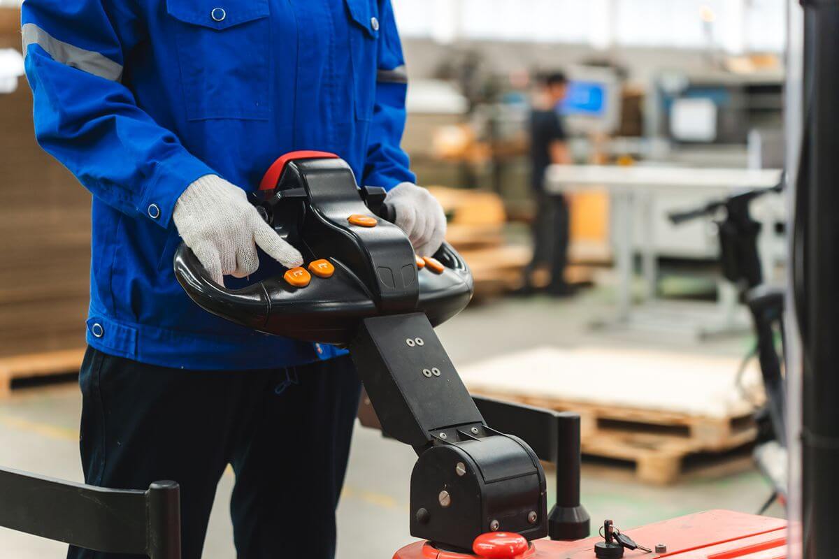 Close-up of electric pallet truck controls showing ergonomic tiller operation for smoother material handling